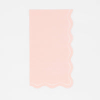 Solid blush pink guest towel with a flowing scalloped white-outlined edge, flat view on white background.