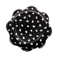 Isolated hero shot of single 10-inch Boo Ghost Scatter plate on pure-white background. Eight-petal scallop rim edged in subtle holographic foil; deep black center sprinkled with dozens of cute ivory ghosts drifting among reflective confetti, evoking starlit sky. Slight drop shadow shows rigid 400 gsm thickness able to hold chili, sandwiches, or cupcakes without sagging. High-resolution image showcases pattern density, foil sheen, and playful design perfect for mix-and-match Halloween party setups.