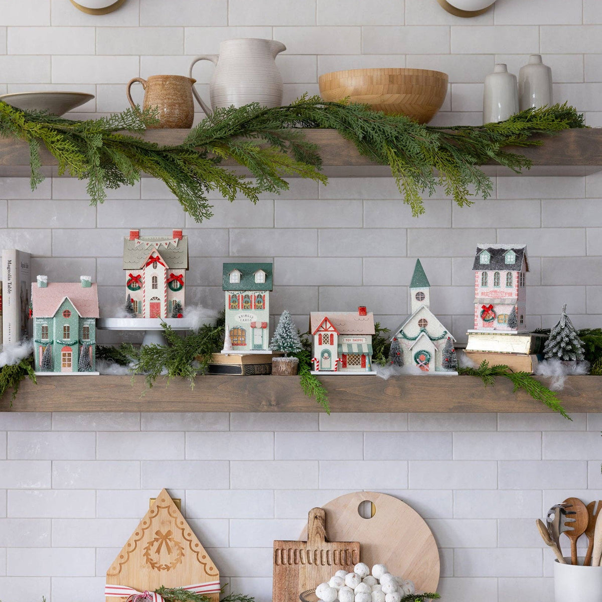 Close-up of the bottom shelf of the Christmas village, detailing the bottlebrush tree accents and paper houses.