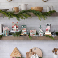 Close-up of the bottom shelf of the Christmas village, detailing the bottlebrush tree accents and paper houses.