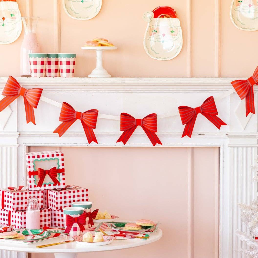Red bow garland displayed over white fireplace with Christmas decor