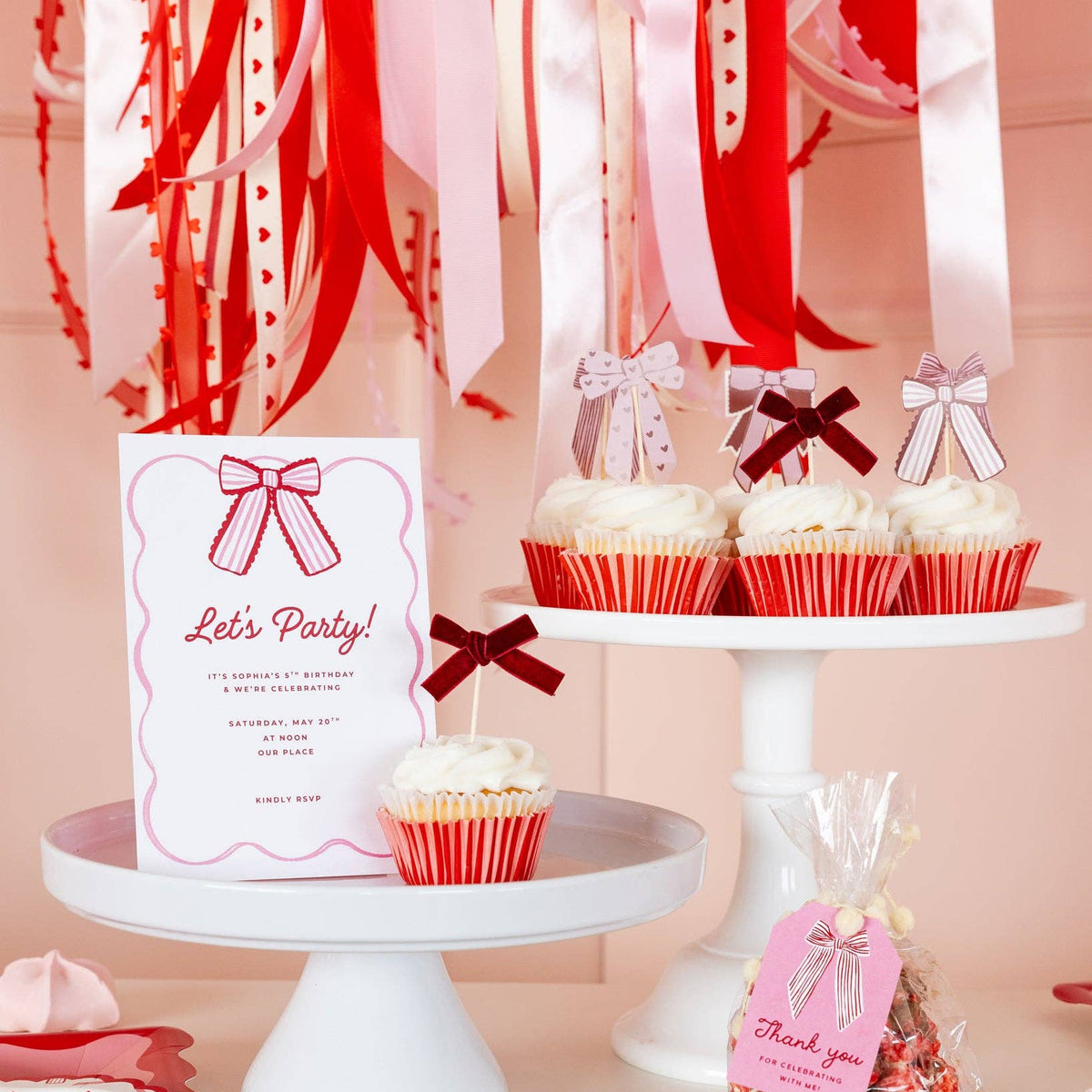 Bow cupcake toppers displayed on frosted cupcakes on dessert stands