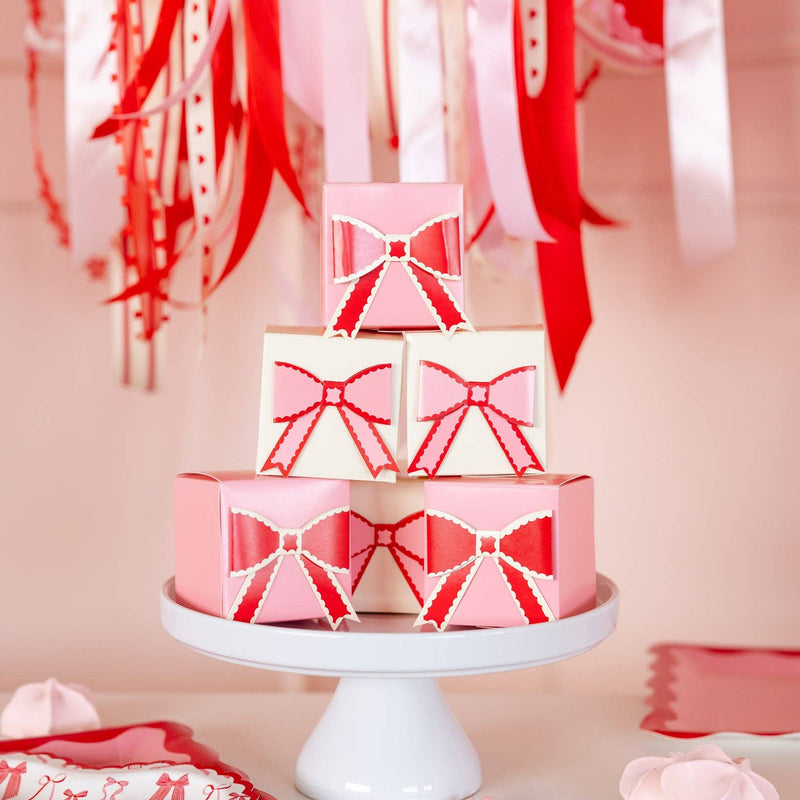Valentine dessert table styled with pink and red bow treat boxes