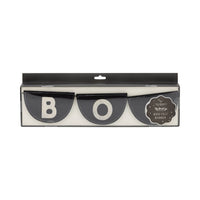 Close-up of retail display box containing Boo felt banner. Transparent window reveals three stacked black pennants—B, O, B—showing half-moon shape, clean white stitching and chunky serif lettering. Hang-tab top signals easy peg-wall merchandising; matte packaging suggests boutique quality. Perfect for e-commerce zoom, this image highlights texture, color accuracy and gift-worthy presentation for shoppers seeking premium Halloween banner décor.
