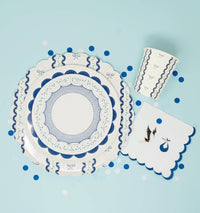 Blue cup styled with a stork napkin and blue confetti on a turquoise background