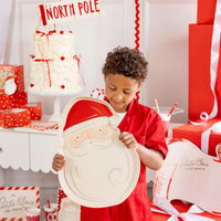 Boy in red outfit looking down at the Christmas serving platter in a holiday display setting.