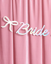 Detail of Bride to Be iridescent banner bow icon and script on pink velvet backdrop