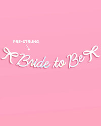 Bride to Be iridescent foil banner with bow accents pre-strung and displayed on pink background