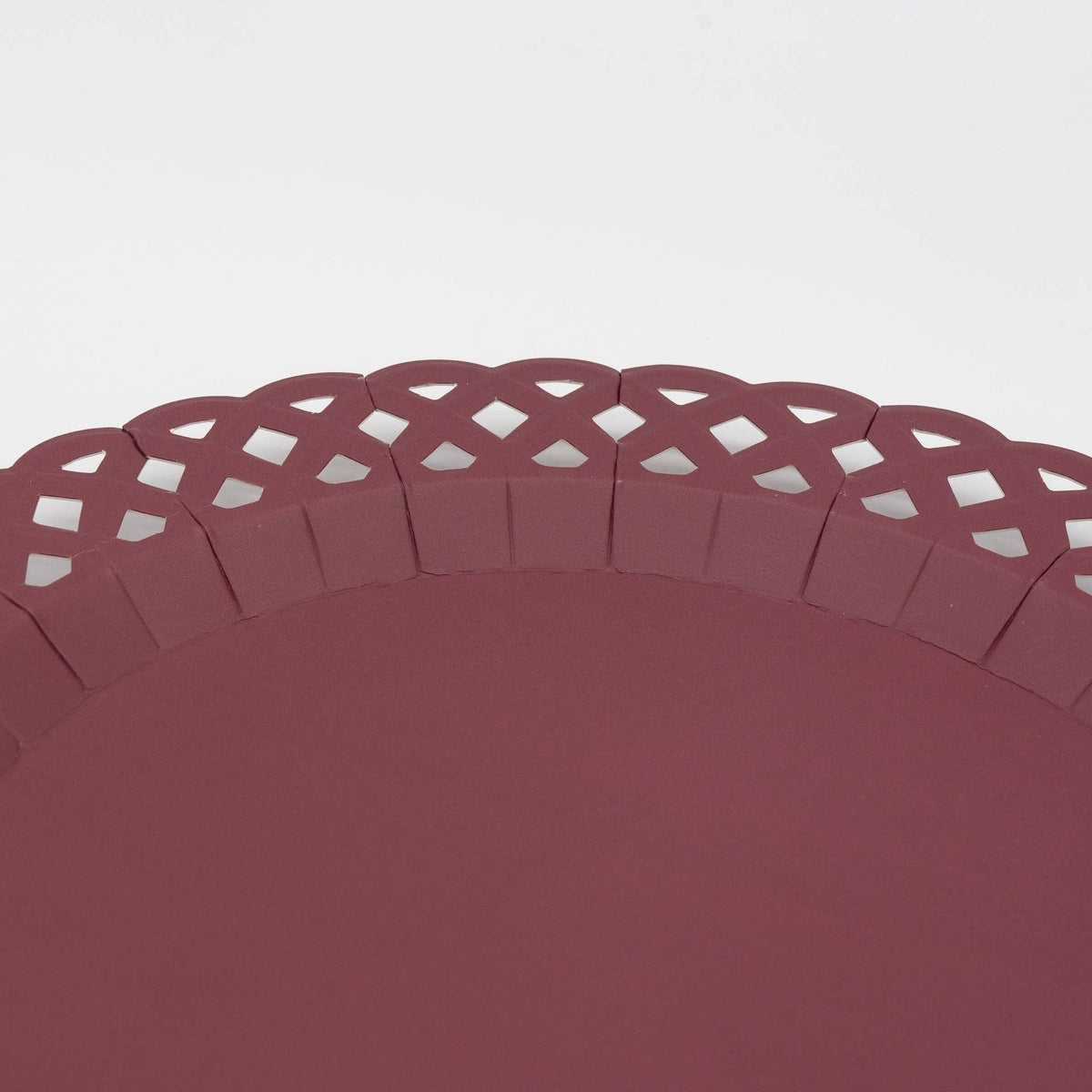 Overhead of a single burgundy basketweave plate showing the full woven texture and scalloped lattice edge.