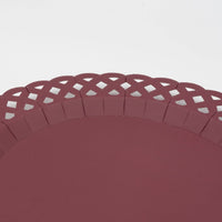 Overhead of a single burgundy basketweave plate showing the full woven texture and scalloped lattice edge.