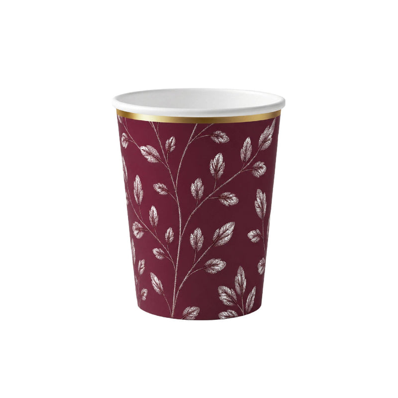 Burgundy paper party cup with an etched white leaf print and gold rim on a white background
