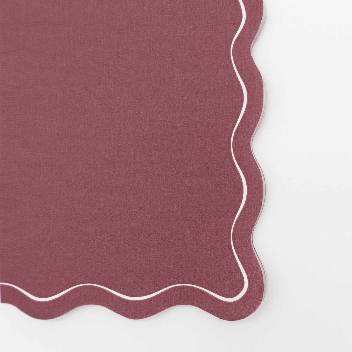 Close-up of the burgundy paper guest towel showing the wavy scalloped edge and cream outline detail.