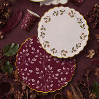 Burgundy leaf dinner plate under a cream berry wreath plate on plum linen with feathers and leaf print cups