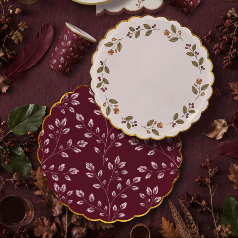 Burgundy leaf dinner plate under a cream berry wreath plate on plum linen with feathers and leaf print cups