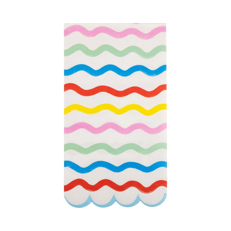 Single unfolded rainbow guest napkin on white background, displaying eight wavy stripes in alternating pastel and primary colors with scalloped bottom edge.