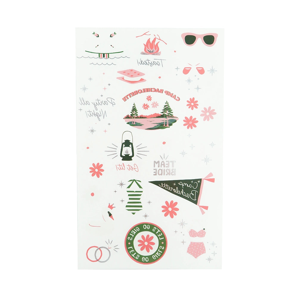 Flat-lay of Camp Bachelorette tattoo sheet featuring 20 pink and green designs like campfire, “Team Bride” pennant, canoe, swimsuit and s’more