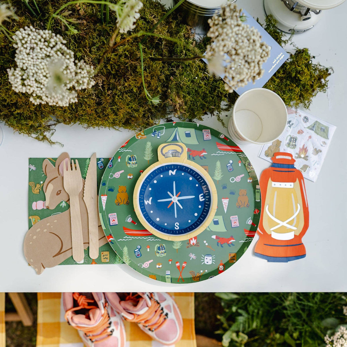 Camp Explorer plate styled on an outdoor table setting with compass centerpiece, wooden cutlery, and lantern