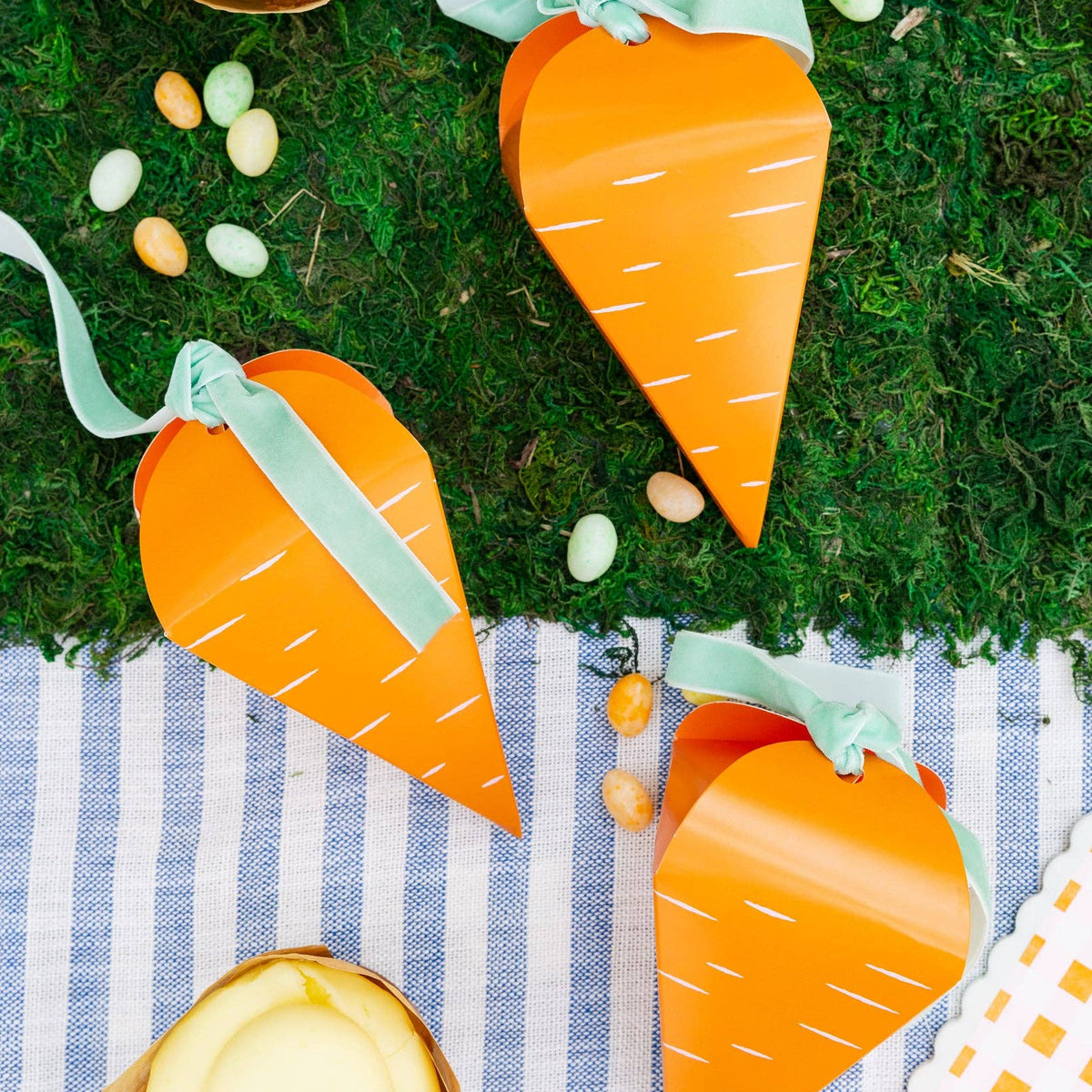 Carrot-shaped treat boxes arranged on a spring table setting with ribbon ties