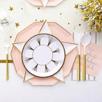 Roaring 1920s NYE tablescape with blush decagonal dinner plate, white star-shaped plate, gold foil champagne coupe paper plate, and blush champagne tower cocktail napkin styled with gold flatware and gold tinsel