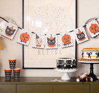 Halloween-themed party setup with decorations, cake, and cups on a table featuring the vintage character banner.