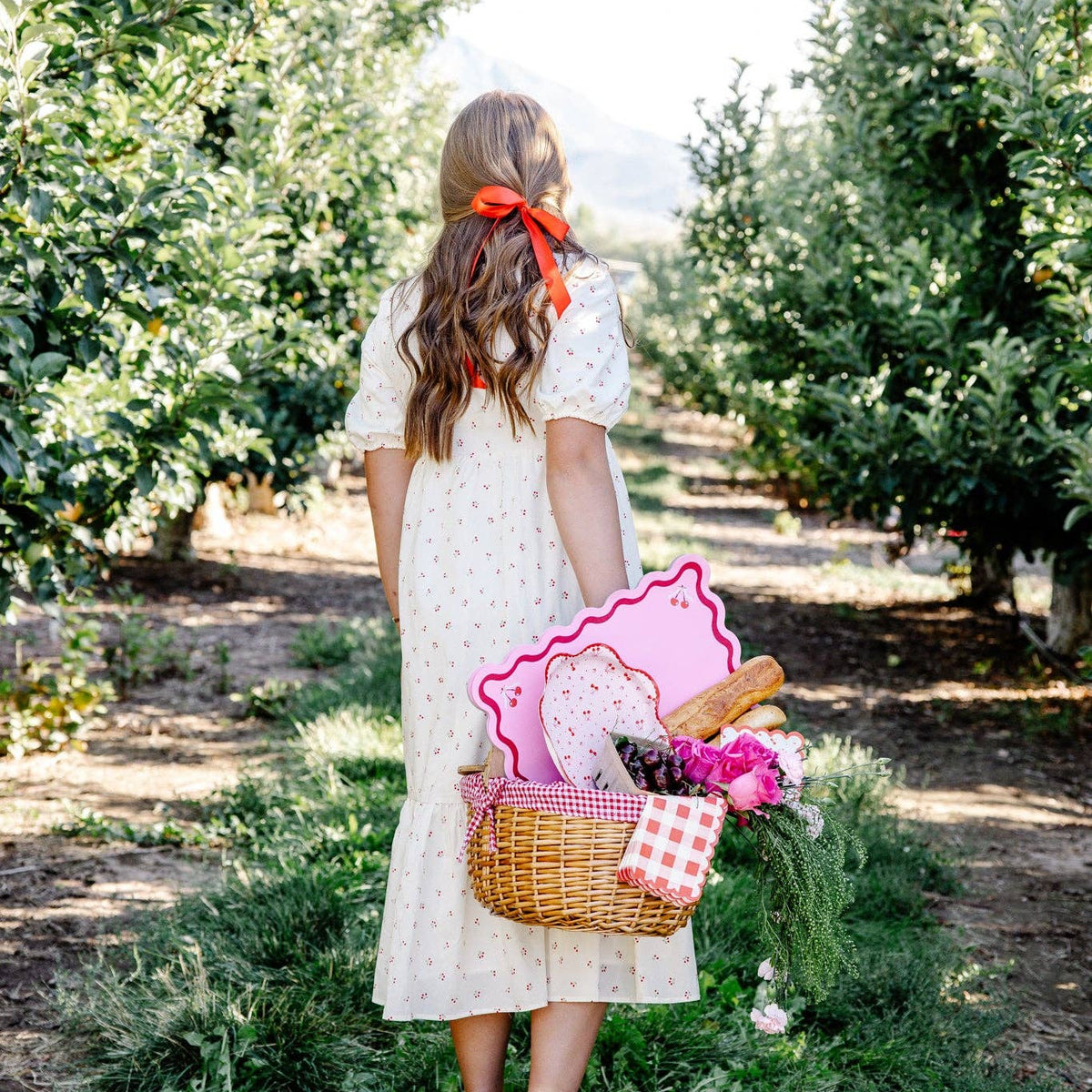 Girl holding picnic basket with cherry placemats outdoors