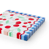 Stack of cherry print paper lunch napkins with gold-foil cherries, mint leaves, a red rickrack edge, and a blue gingham border.