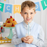 Child holding drink with colored pencil reusable straw.