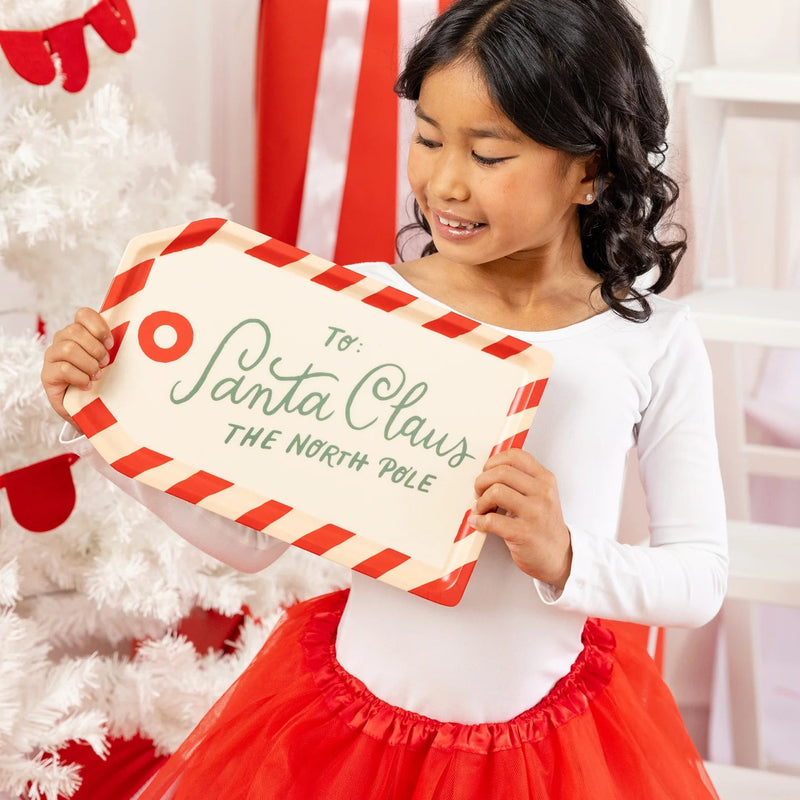 Young girl holding up the small Santa tag bamboo tray in a red and white holiday setting.