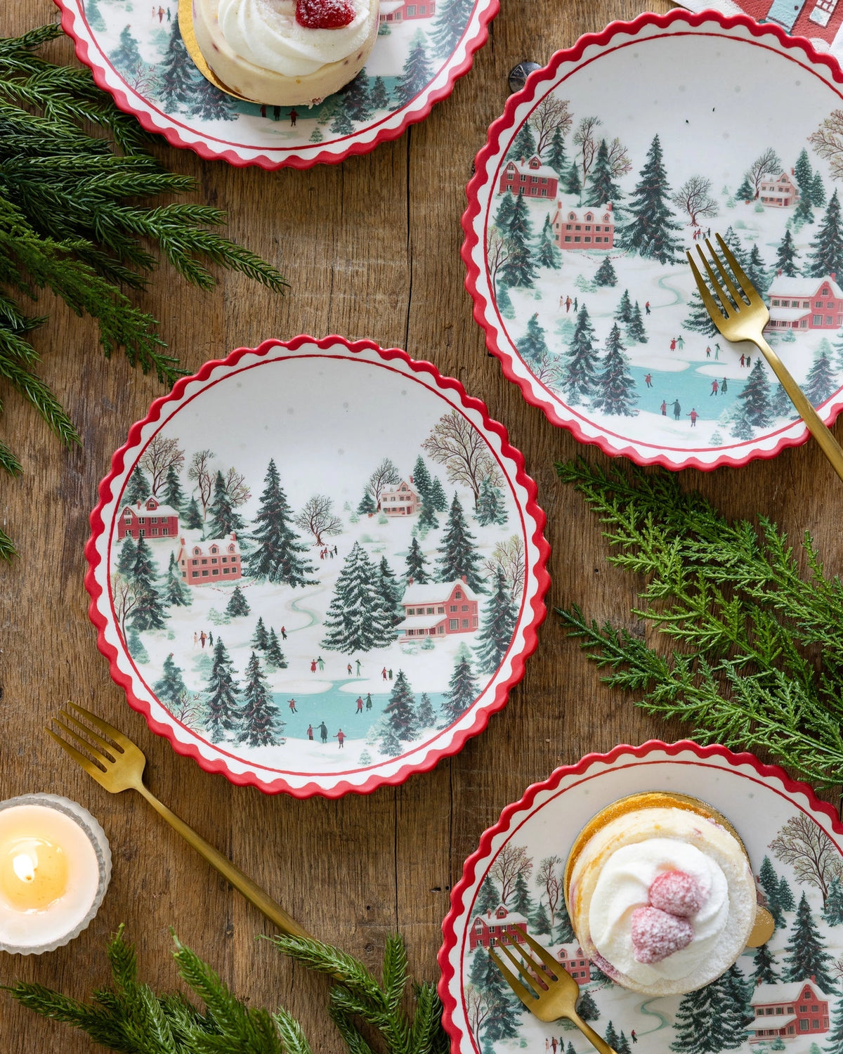 Christmas village bamboo plates on a wood table with a candle and place setting.