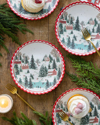 Christmas village bamboo plates on a wood table with a candle and place setting.