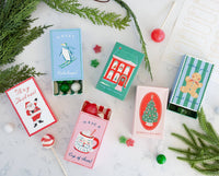 Christmas treat boxes open on marble counter with gumballs, lollipops, and gumdrop candies