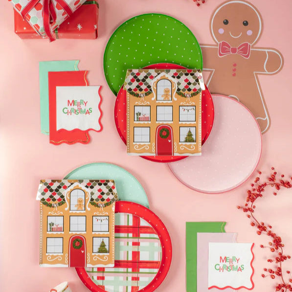 Flat lay with wrapped gifts, gingerbread décor, and colorful dotted Christmas paper plates.