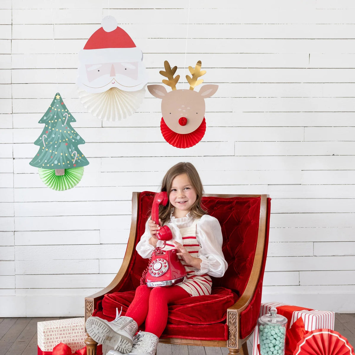 Lifestyle scene with child on phone under 3D Christmas hanging decorations (Santa, reindeer, tree)