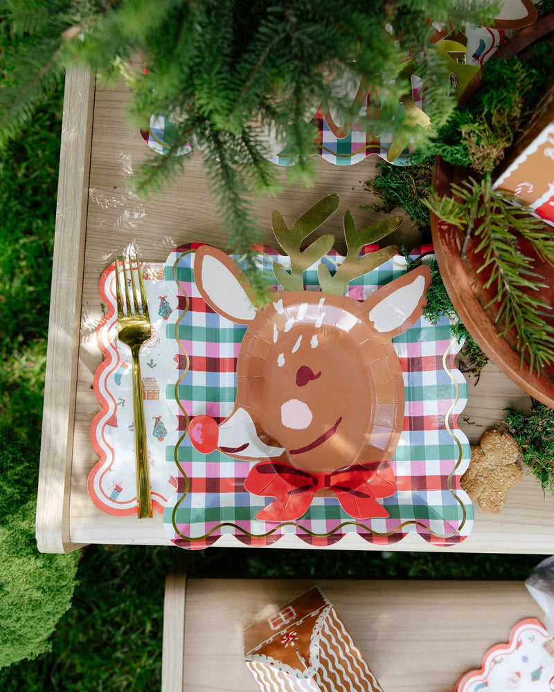 Christmas icon paper dinner napkin with a gold fork beside a reindeer plate on a gingham plate; plates and fork shown separately, not included
