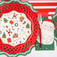 Place setting with a Christmas icon activity plate on a red lattice charger, a Santa napkin, and the green star guest towel.