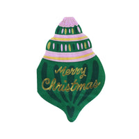 Die-cut Christmas ornament shaped napkin in green with "Merry Christmas" in gold script and pink-and-white banded detailing, front view on white background.