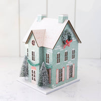 Angled view of a mint putz house showing a frosted wreath with a red bow on the side gable