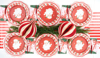 Overhead with striped ornaments, Santa plates, red doily chargers, and green star guest towels.