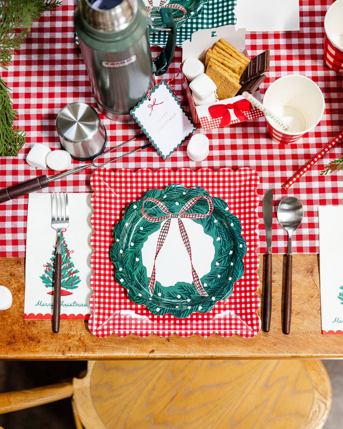 The Christmas tree napkin on a gingham table with a wreath plate and holiday place setting.