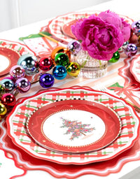 Overhead of a Christmas-tree plate on the plaid dinner plate with multicolor ornaments and pink peonies.