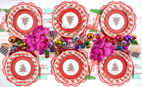 Overhead of Christmas-tree plates on plaid plates with pink peonies and multicolor ornaments.