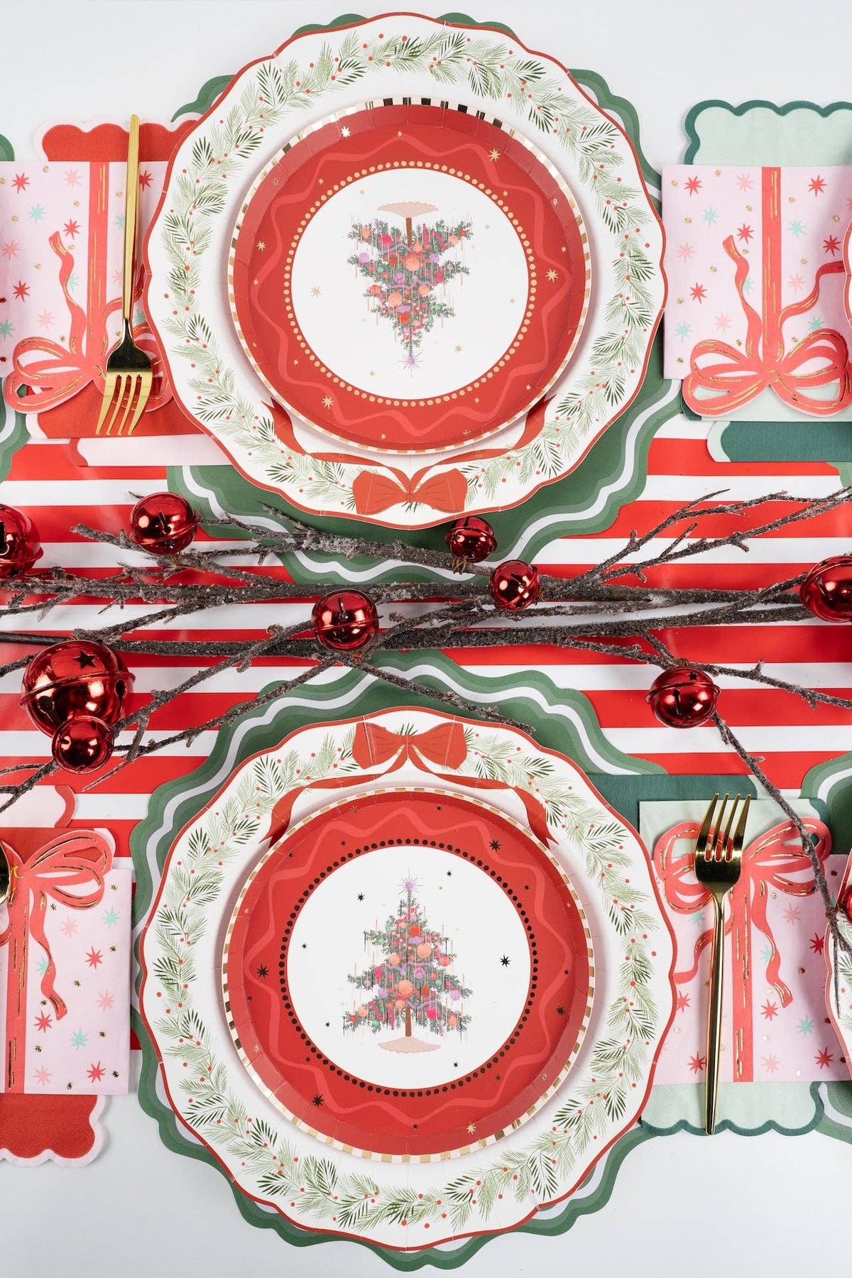 Overhead mirrored settings with Christmas-tree holly-rim plates, a red-and-white striped runner, red ornament sprigs, and red bows.