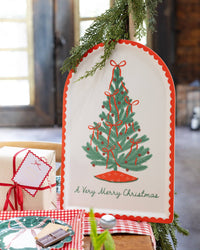 The bamboo tray propped on a rustic console with a Christmas tree and greenery.