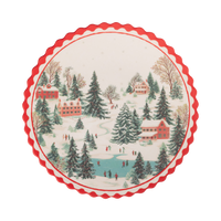 Round cream bamboo plate with a snowy Christmas village scene and a red scalloped edge.