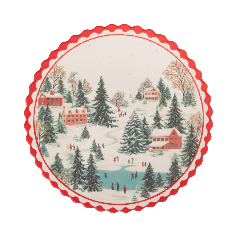 Round cream bamboo plate with a snowy Christmas village scene and a red scalloped edge.
