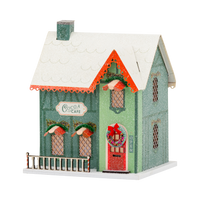 Green glitter cocoa cafe putz house with snowy roof, red door wreath, and candy striped porch rail