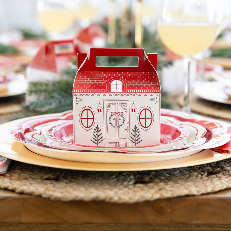 Close-up of the Christmas cottage box placed on a holiday table place setting with layered plates and greenery.