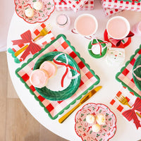 Close-up of the Christmas plates layered on the plaid base plate, surrounded by gold cutlery and pink drinks.