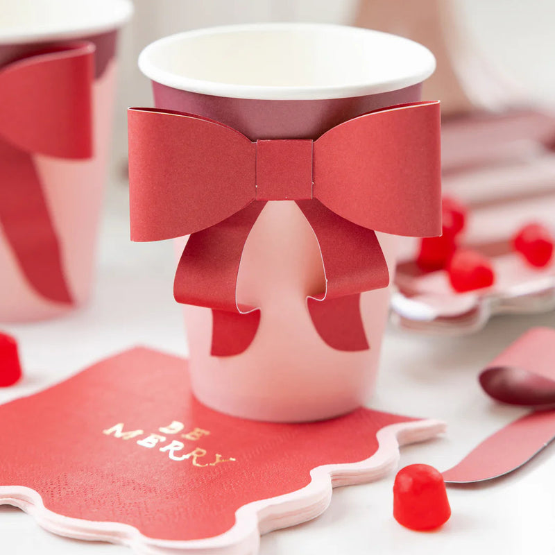 Close-up of the assembled bow cups with red bow wraps, displayed with matching red and pink party supplies napkins and candy.
