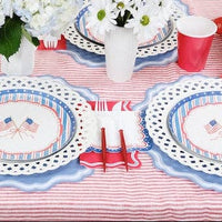 A Grandmillennial July 4th Decor table featuring flag plates and white scalloped chargers.